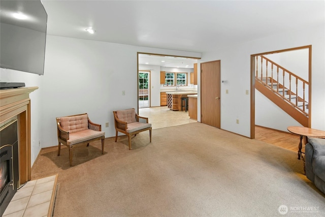 living area with recessed lighting, a lit fireplace, stairs, and light colored carpet