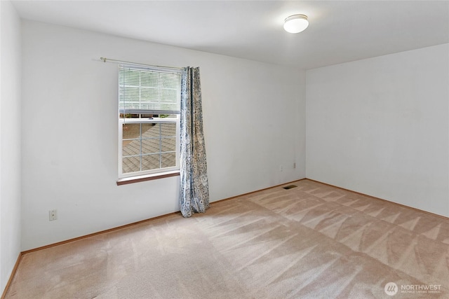 carpeted spare room featuring baseboards and visible vents