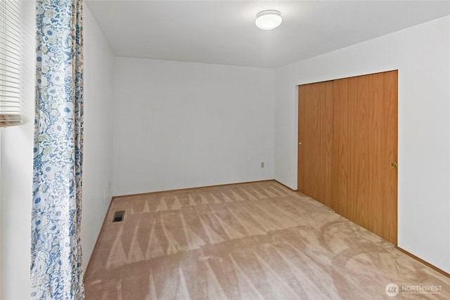 unfurnished bedroom with carpet floors, a closet, and visible vents