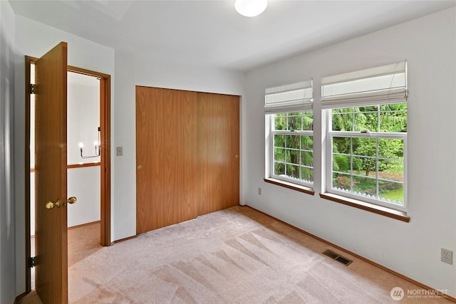 unfurnished bedroom with light colored carpet, baseboards, visible vents, and a closet
