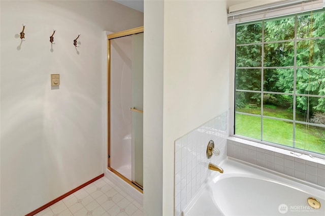 bathroom featuring baseboards, a garden tub, and a stall shower