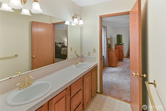ensuite bathroom with a sink, ensuite bathroom, double vanity, and a notable chandelier