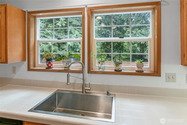 kitchen with a sink, tile countertops, and a healthy amount of sunlight