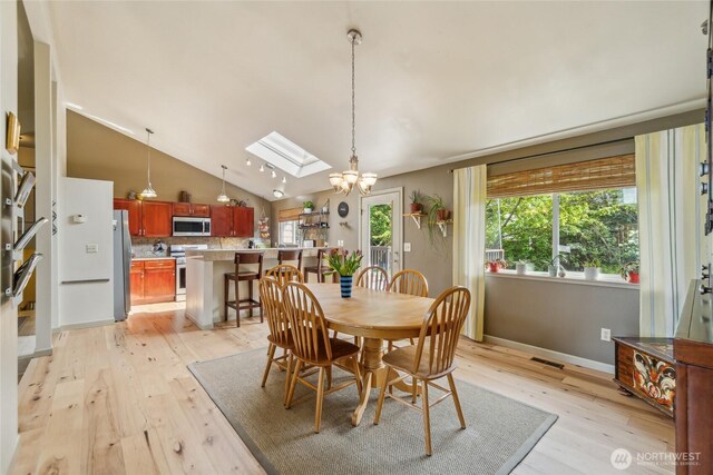 dining space featuring visible vents, a chandelier, lofted ceiling with skylight, and light wood-type flooring