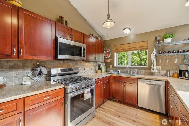 kitchen with lofted ceiling, light wood-type flooring, a sink, appliances with stainless steel finishes, and backsplash