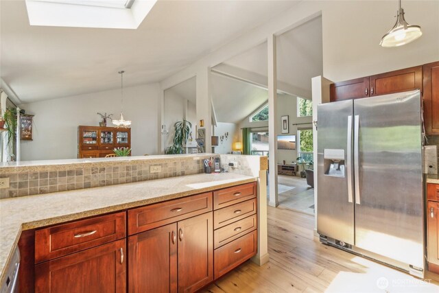 bathroom with an inviting chandelier, backsplash, lofted ceiling with skylight, and wood finished floors
