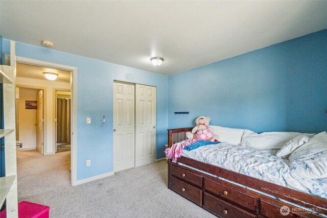 bedroom featuring baseboards, light colored carpet, and a closet