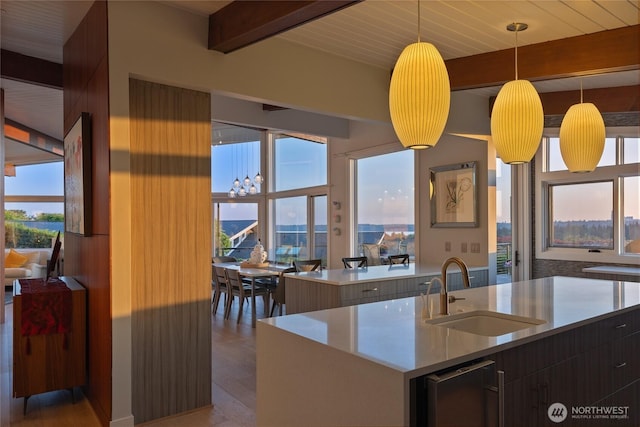 kitchen featuring light countertops, beam ceiling, a sink, and wood finished floors