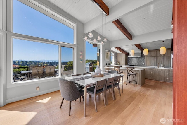 dining room with beam ceiling, visible vents, and light wood-style flooring