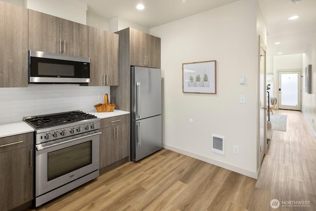 2612A SW Nevada St, Seattle, WA 98126 - kitchen with stainless steel appliances, light wood-style floors, decorative backsplash, light countertops, and baseboards