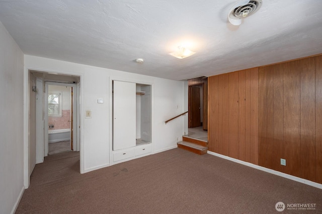 interior space with wooden walls, baseboards, and carpet flooring
