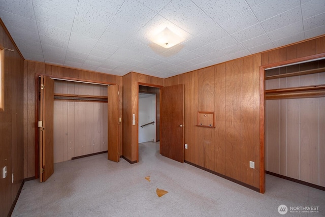unfurnished bedroom featuring wooden walls, a closet, and carpet flooring