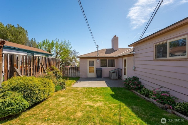 rear view of property with a lawn, a patio area, fence, and a chimney