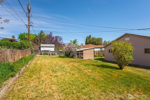 view of yard with an outdoor structure, fence, and a storage shed