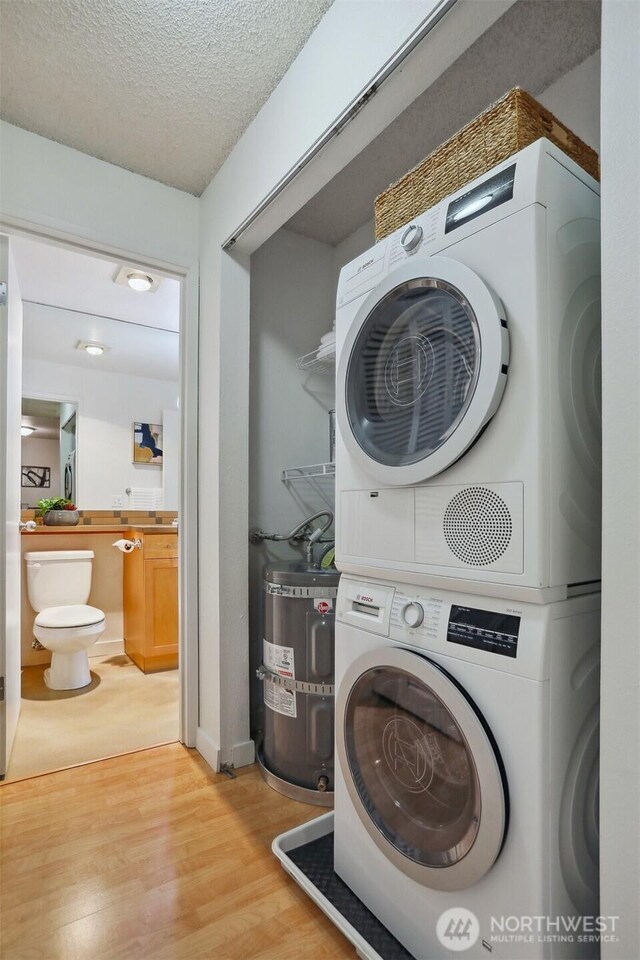 275 W Roy St Unit 216, Seattle, WA 98119 - laundry room featuring laundry area, a textured ceiling, stacked washing maching and dryer, light wood-style flooring, and secured water heater