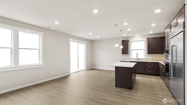 kitchen with dark brown cabinetry, light wood finished floors, baseboards, tasteful backsplash, and a kitchen island