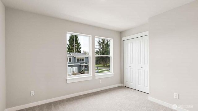 unfurnished bedroom featuring carpet floors, baseboards, and a closet