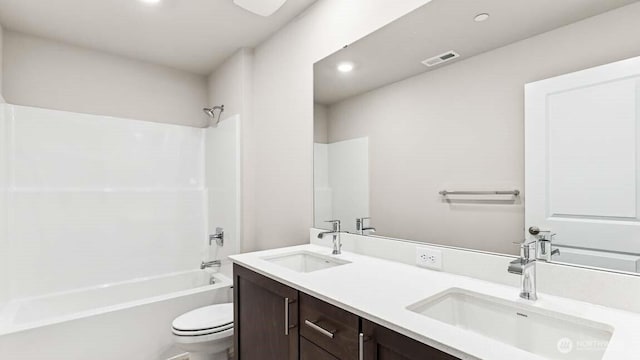 bathroom with toilet, visible vents, tub / shower combination, and a sink