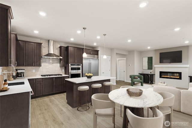 13447 NE 104th Way Unit 3, Kirkland, WA 98033 - kitchen with wall chimney exhaust hood, appliances with stainless steel finishes, open floor plan, dark brown cabinets, and a center island