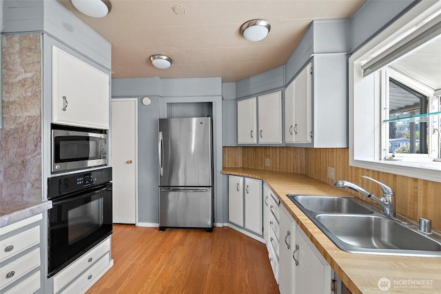 1402 22nd St NE Unit 65, Auburn, WA 98002 - kitchen with appliances with stainless steel finishes, a sink, light countertops, and light wood-style flooring