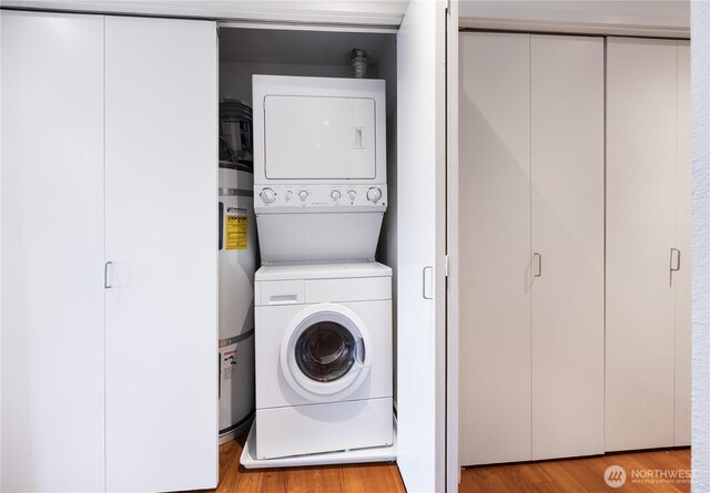 washroom with water heater, stacked washer and clothes dryer, light wood-style flooring, and laundry area