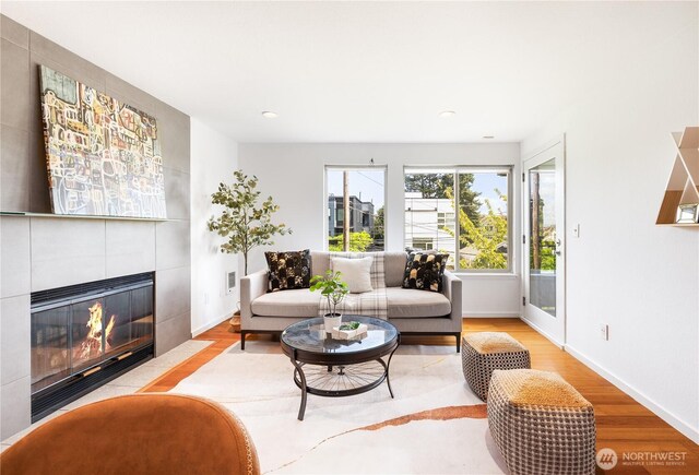 living area with a tiled fireplace, recessed lighting, and wood finished floors