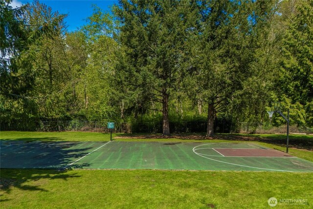 view of basketball court with fence, community basketball court, and a lawn