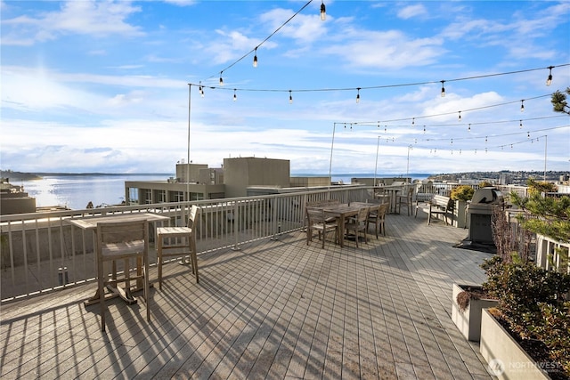 view of patio featuring outdoor dining area, a deck with water view, and a grill