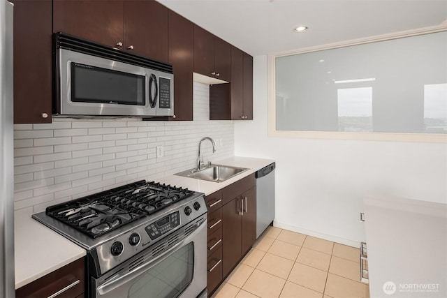 kitchen with dark brown cabinetry, light countertops, a sink, appliances with stainless steel finishes, and backsplash