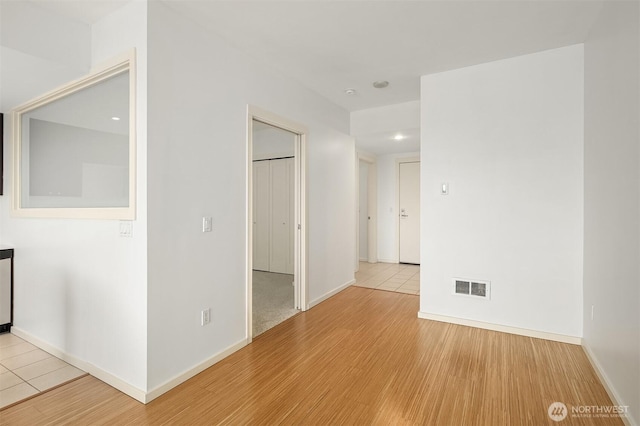 spare room with baseboards, visible vents, and wood finished floors