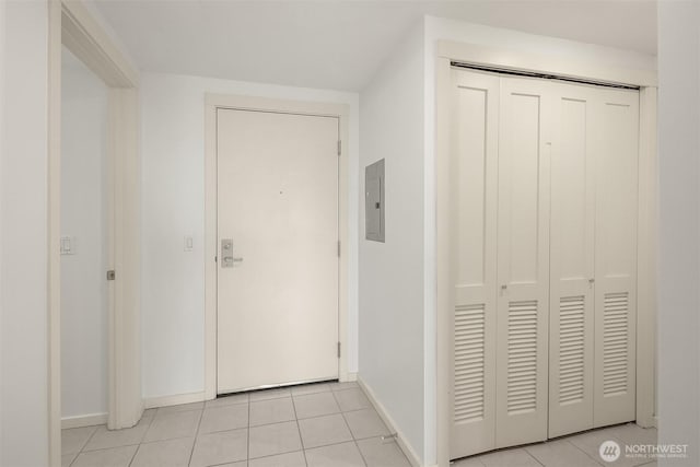 hall featuring baseboards, electric panel, and light tile patterned flooring