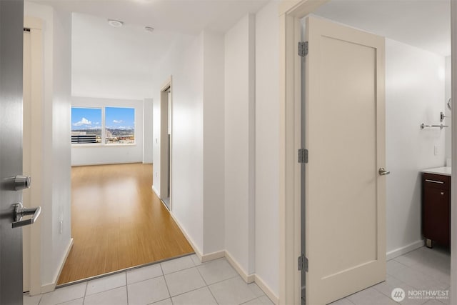 corridor featuring light tile patterned floors and baseboards