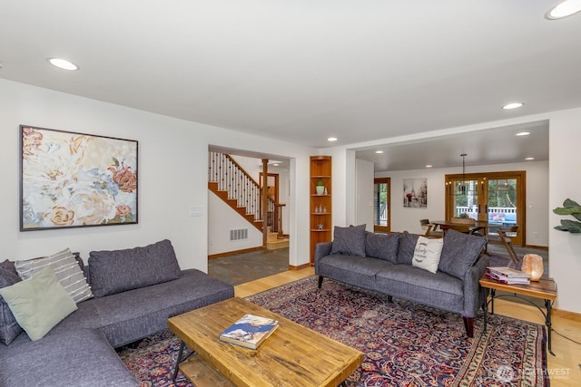 living area with recessed lighting, baseboards, wood finished floors, and stairway