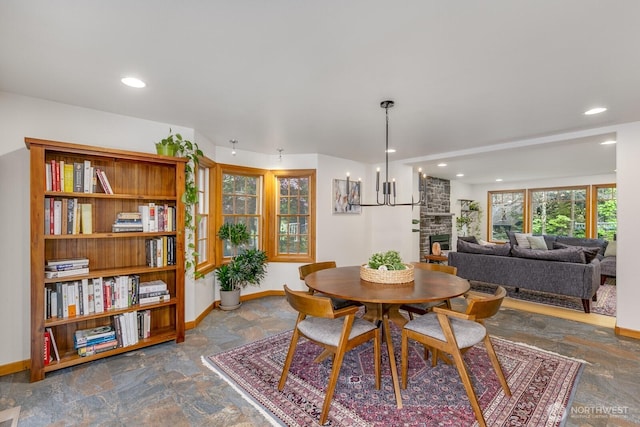 dining room featuring baseboards, stone finish floor, and a fireplace