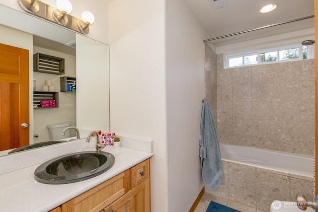 full bathroom featuring tiled shower / bath combo, toilet, visible vents, and vanity