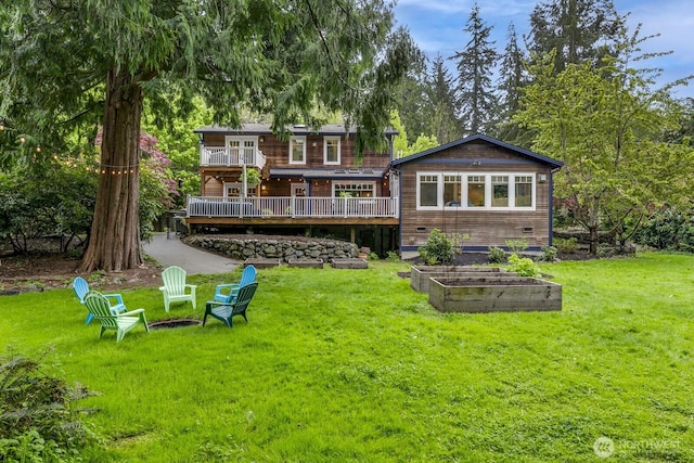 back of house with a wooden deck, a yard, and a vegetable garden