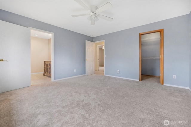 unfurnished bedroom featuring baseboards, a walk in closet, and carpet