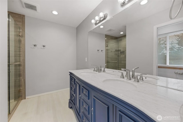bathroom with a stall shower, visible vents, a sink, and wood finished floors
