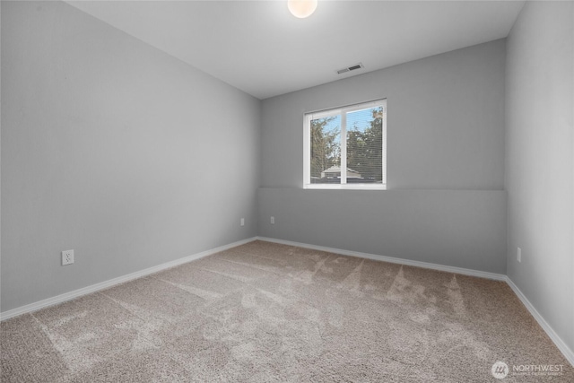 empty room with carpet floors, baseboards, and visible vents
