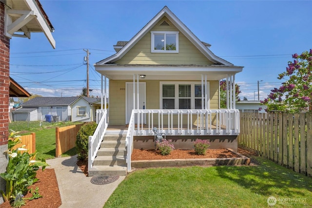 bungalow-style house featuring covered porch, fence, and a front yard