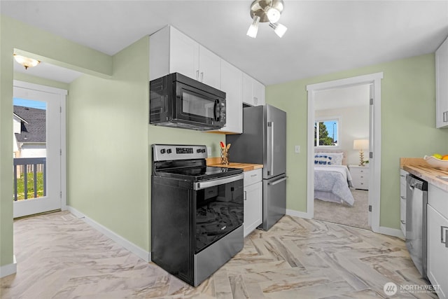 kitchen featuring white cabinets, baseboards, appliances with stainless steel finishes, and a wealth of natural light