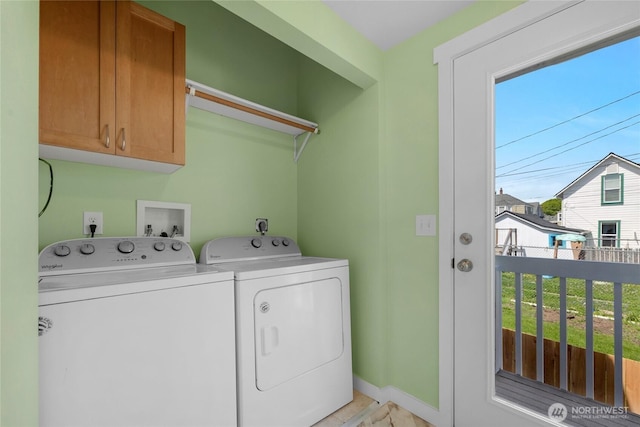 clothes washing area featuring separate washer and dryer, baseboards, and cabinet space
