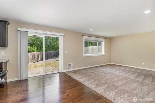empty room with baseboards, visible vents, a wealth of natural light, and wood finished floors