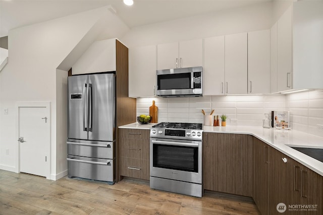 2414 NW 64th St Unit A, Seattle, WA 98107 - kitchen with stainless steel appliances, light countertops, light wood-style flooring, decorative backsplash, and recessed lighting