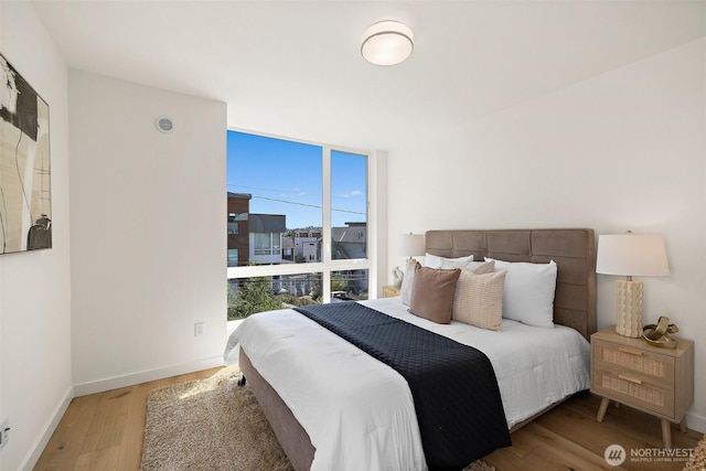 2414 NW 64th St Unit A, Seattle, WA 98107 - bedroom featuring wood finished floors, a wall of windows, and baseboards