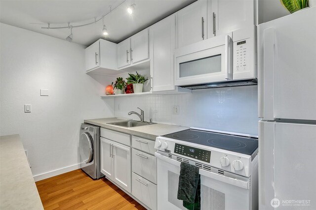 kitchen with washer / clothes dryer, a sink, baseboards, light countertops, and white appliances