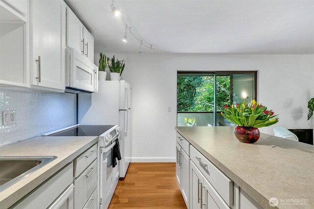 kitchen with decorative backsplash, white appliances, light countertops, white cabinetry, and light wood finished floors
