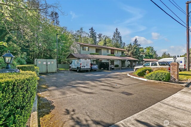 view of front of property featuring covered and uncovered parking and fence