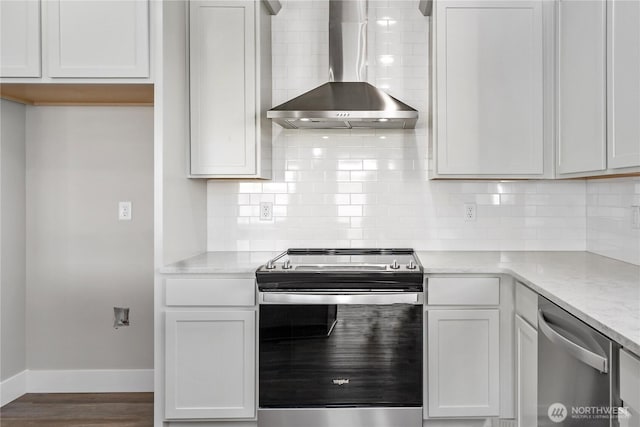 kitchen featuring wall chimney exhaust hood, stainless steel appliances, baseboards, decorative backsplash, and wood finished floors