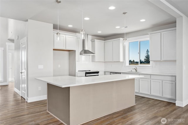 kitchen with wall chimney range hood, a kitchen island, dark wood-style flooring, appliances with stainless steel finishes, and white cabinetry